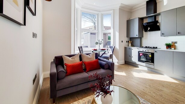 A modern kitchen with grey cabinets, a built-in oven, and a black range hood. - Lovely 1-bed Apartment in London With Courtyard (London)