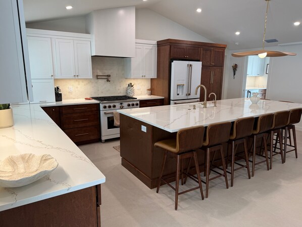 Una cocina moderna con una isla central, electrodomésticos de acero inoxidable y una zona de asientos tipo barra.