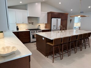 A modern kitchen with a central island, stainless steel appliances, and a bar seating area.