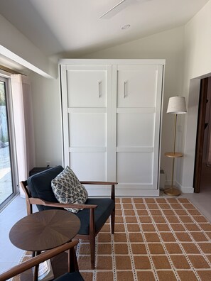 A room with a sofa, a small round table, a floor lamp, and a large wardrobe.