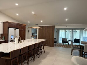 A modern kitchen with a large island, wooden cabinets, and a built-in refrigerator.