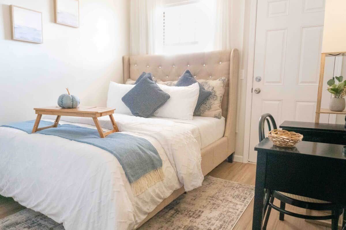 A bedroom with a bed, bedside table, and a desk with a chair.
