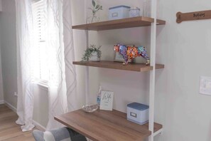 A room with a wooden desk, a potted plant, a decorative dog bone, and a framed sign.