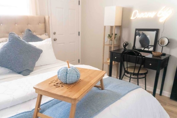 A bedroom with a bed, bedside table, lamp, chair, desk, and a neon sign. - Casita Moderna | Near SWOSU, Downtown, & I-40! (Weatherford)