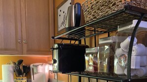 Une cuisine avec un grille-pain noir, une machine à café et une bouilloire posées sur une étagère.
