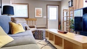 Un salon avec un canapé, une table basse, un téléviseur et une bibliothèque.