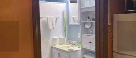 A compact bathroom with a toilet, sink, and shower area.