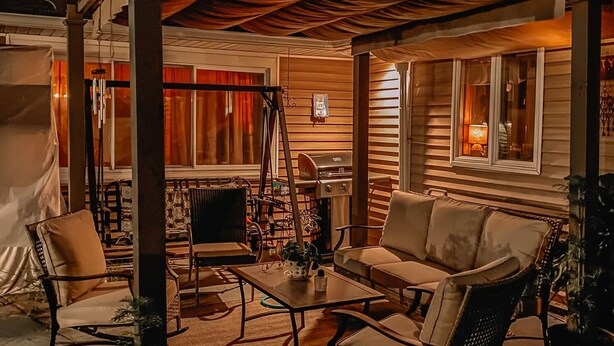 Un espace extérieur aménagé en patio, avec un coin salon abrité, une table à manger et une cheminée.