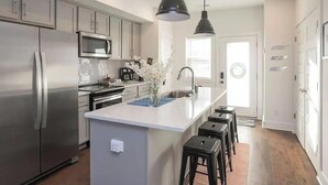 A modern kitchen with a central island, stainless steel appliances, and pendant lighting.