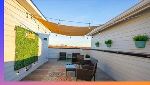 A covered outdoor patio with a seating area, string lights, and potted plants.