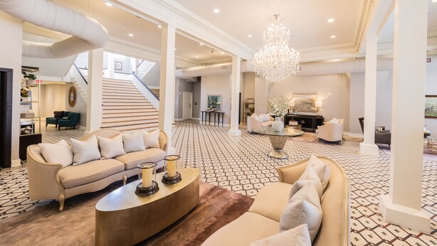 A spacious living area with a large chandelier, a sofa set, a coffee table, and a patterned floor. - The Blanche  (Lake City)