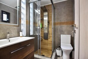 A modern bathroom with a glass-enclosed shower, a white sink, and a toilet. - Modern Villa in Heraklion City Center, Crete (Heraklion)