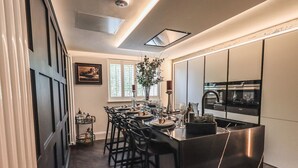 Une cuisine moderne dotée d’un îlot central, de tabourets de bar et d’un coin repas avec une grande fenêtre.