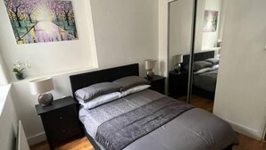 Ein Schlafzimmer mit Bett, Nachttischen, einem Spiegel und einem Bild an der Wand.