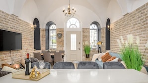 A spacious dining area with a marble table, grey upholstered chairs, and a chandelier. - Nina Luxury Apartment (Jerusalem)