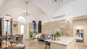 A spacious living area with a high ceiling, a dining table, and a cozy seating arrangement. - Nina Luxury Apartment (Jerusalem)