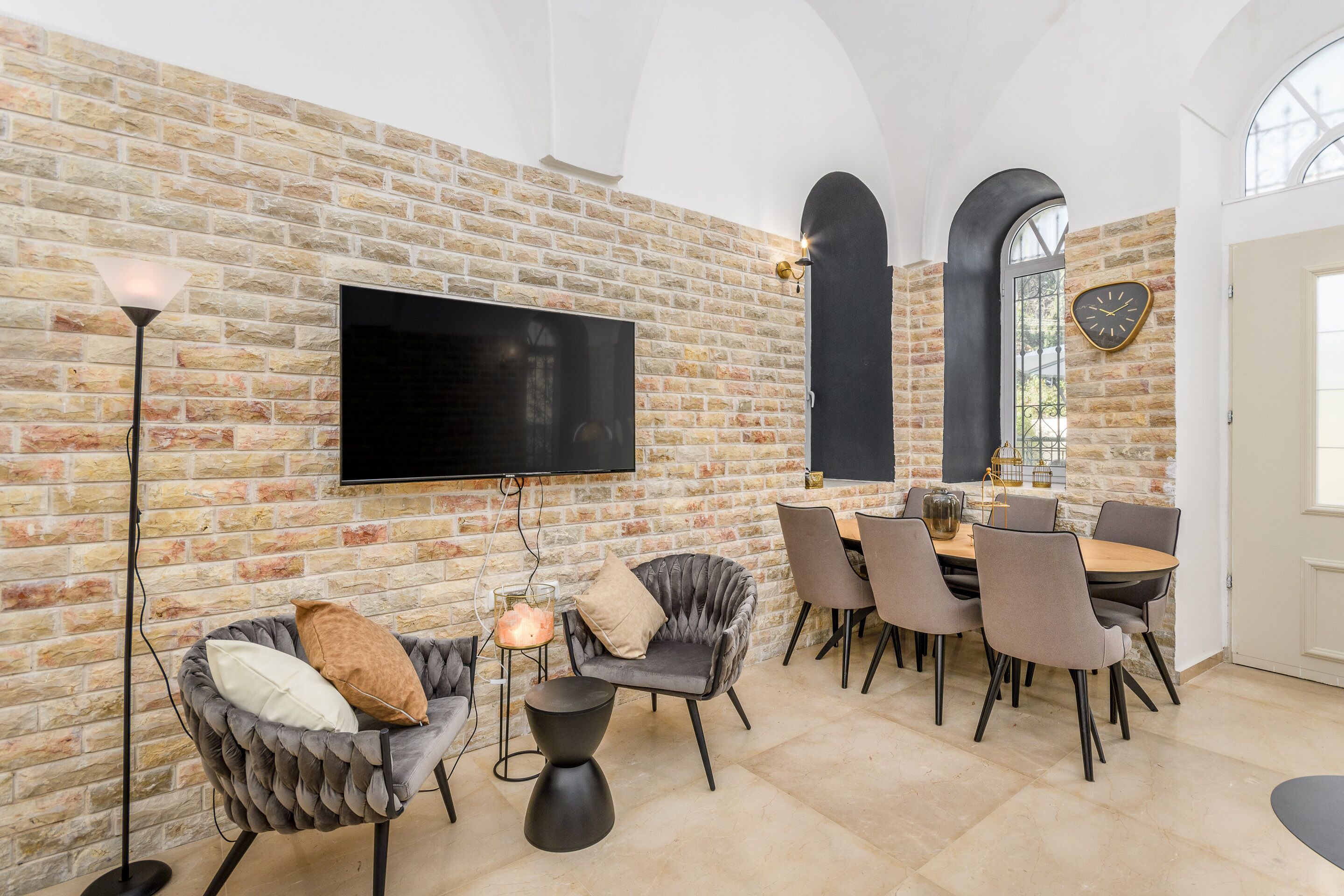 Un espace repas agrémenté d’un mur en briques, d’un téléviseur à écran plat et de mobilier moderne.