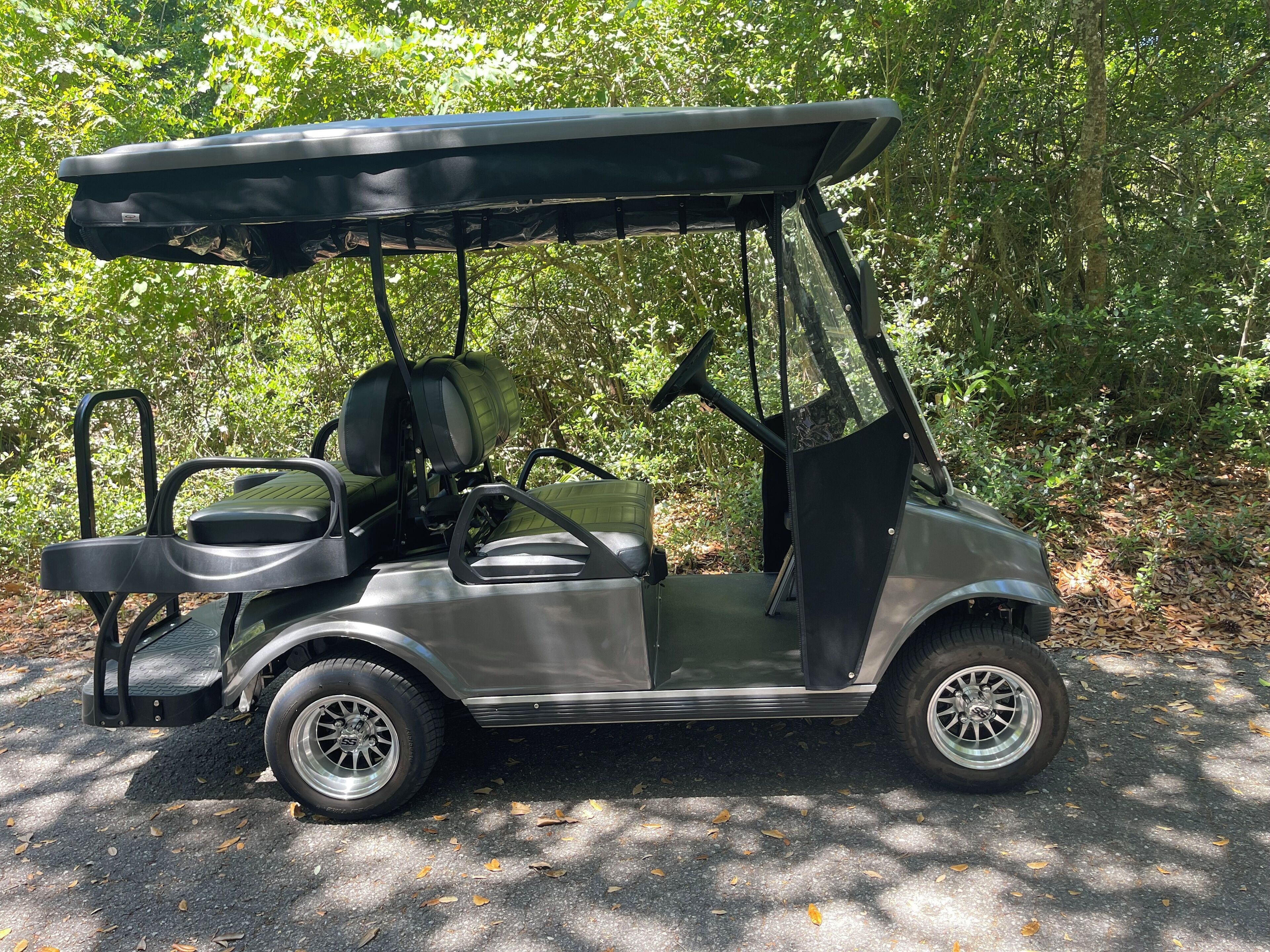 Ein Golfmobil steht auf einem gepflasterten Weg, umgeben von Bäumen.