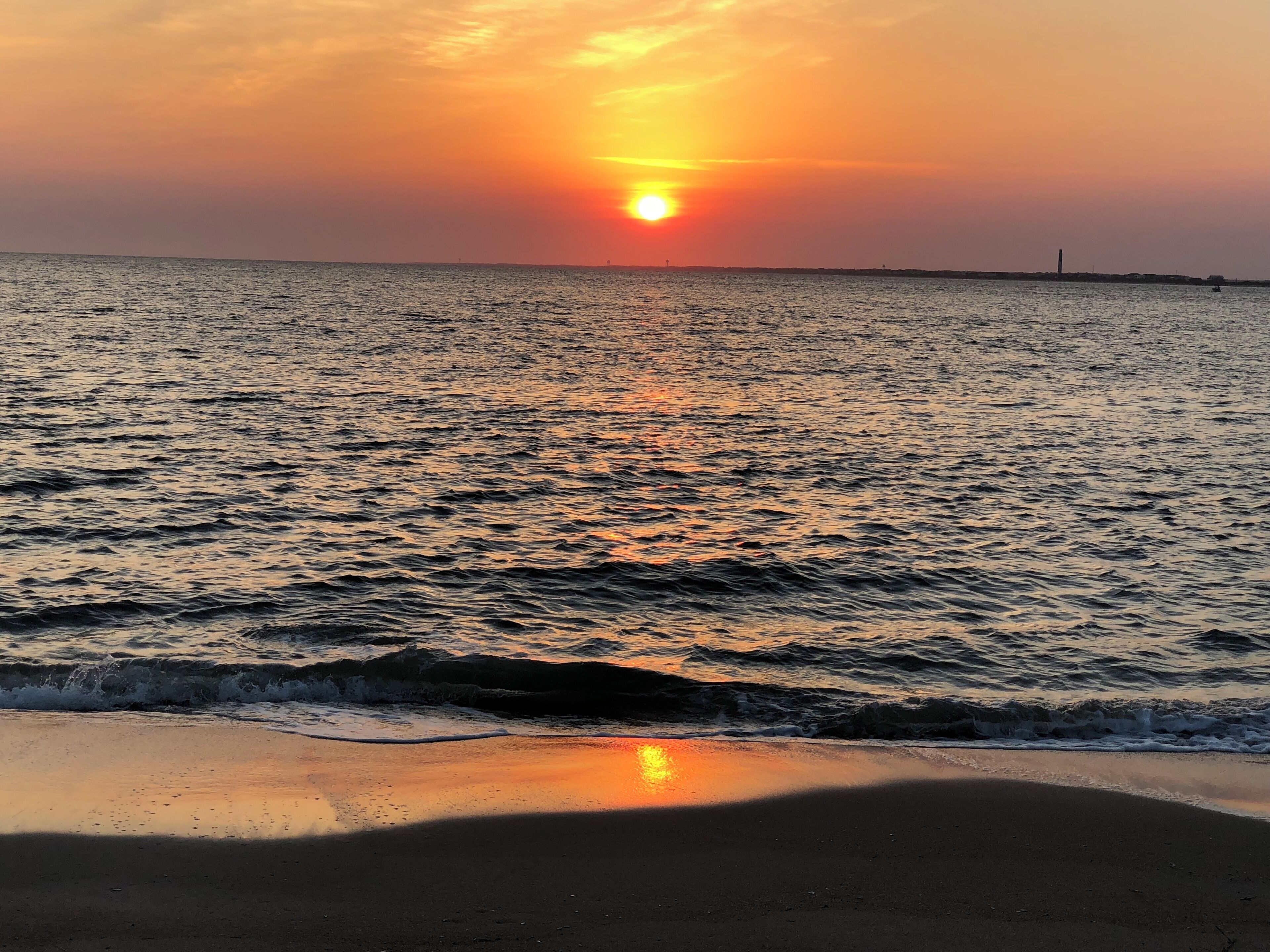 A sunset over a calm sea with gentle waves, reflecting the sky's colors.