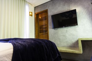 Ein Hotelzimmer mit einem Bett, einem an der Wand befestigten Fernseher und einer Holztür.