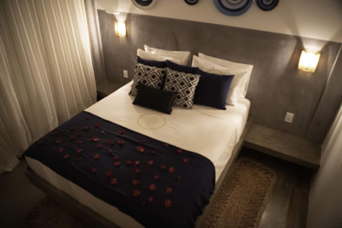 Une chambre d’hôtel avec un lit, des oreillers, une couverture et des appliques murales.