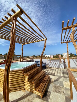 Una estructura de pérgola de madera con piscina y zona de estar en una terraza en la azotea.