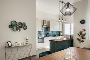 Enjoy cooking in the well-equipped kitchen with a central island, white cabinetry, and a backsplash featuring a mosaic tile pattern.