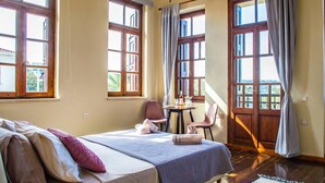 A room with a bed, a table with chairs, and large windows with curtains. - Ruby Studio - Old Town Rethymno (Rethymno)