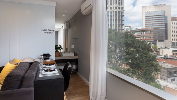A modern living room with a sofa, dining table, and a view of the cityscape. - VN Ferreira Lobo (São Paulo)