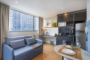 A modern apartment with a living area, kitchenette, and dining space.