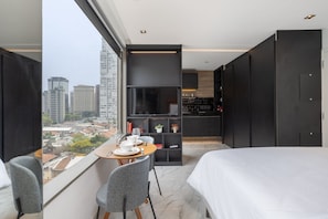 A modern hotel room with a large bed, a dining area with a table and chairs, a TV, and a city view. - VN Ferreira Lobo (São Paulo)