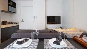 A modern living space with a dining area, kitchen, and a flat-screen TV mounted on the wall. - VN Ferreira Lobo (São Paulo)