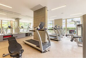Une salle de sport équipée de tapis de course, de vélos d’exercice et d’appareils de musculation.