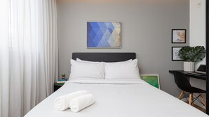 A neatly made bed with white linens, a headboard, and two rolled towels. - VN Ferreira Lobo (São Paulo)