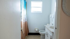 Et lille badeværelse med toilet, vask og et vindue.