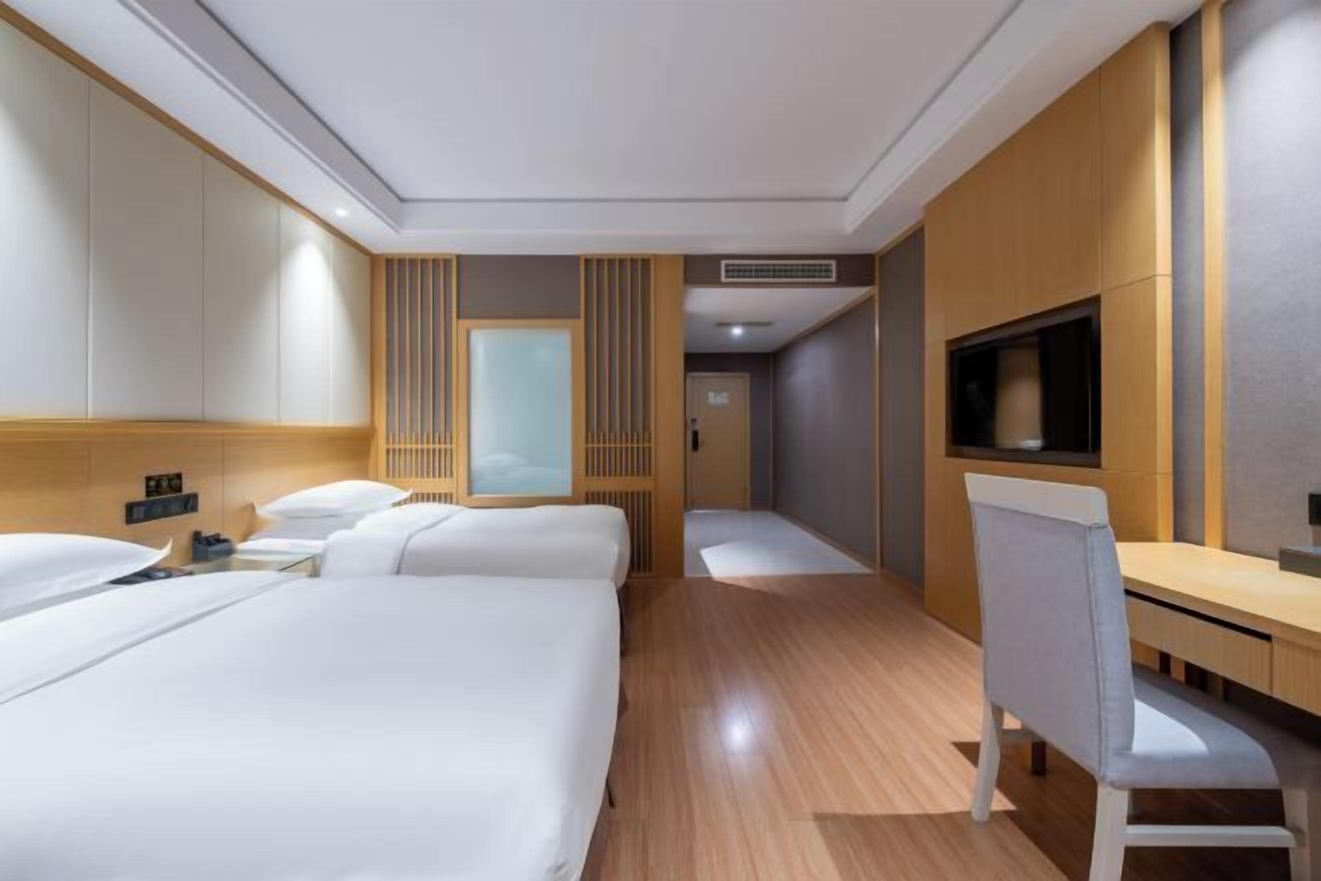Una habitación de hotel con dos camas, un escritorio, una silla, un televisor y un armario.