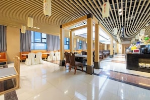 A hotel lobby with seating areas, a reception desk, and a food counter.