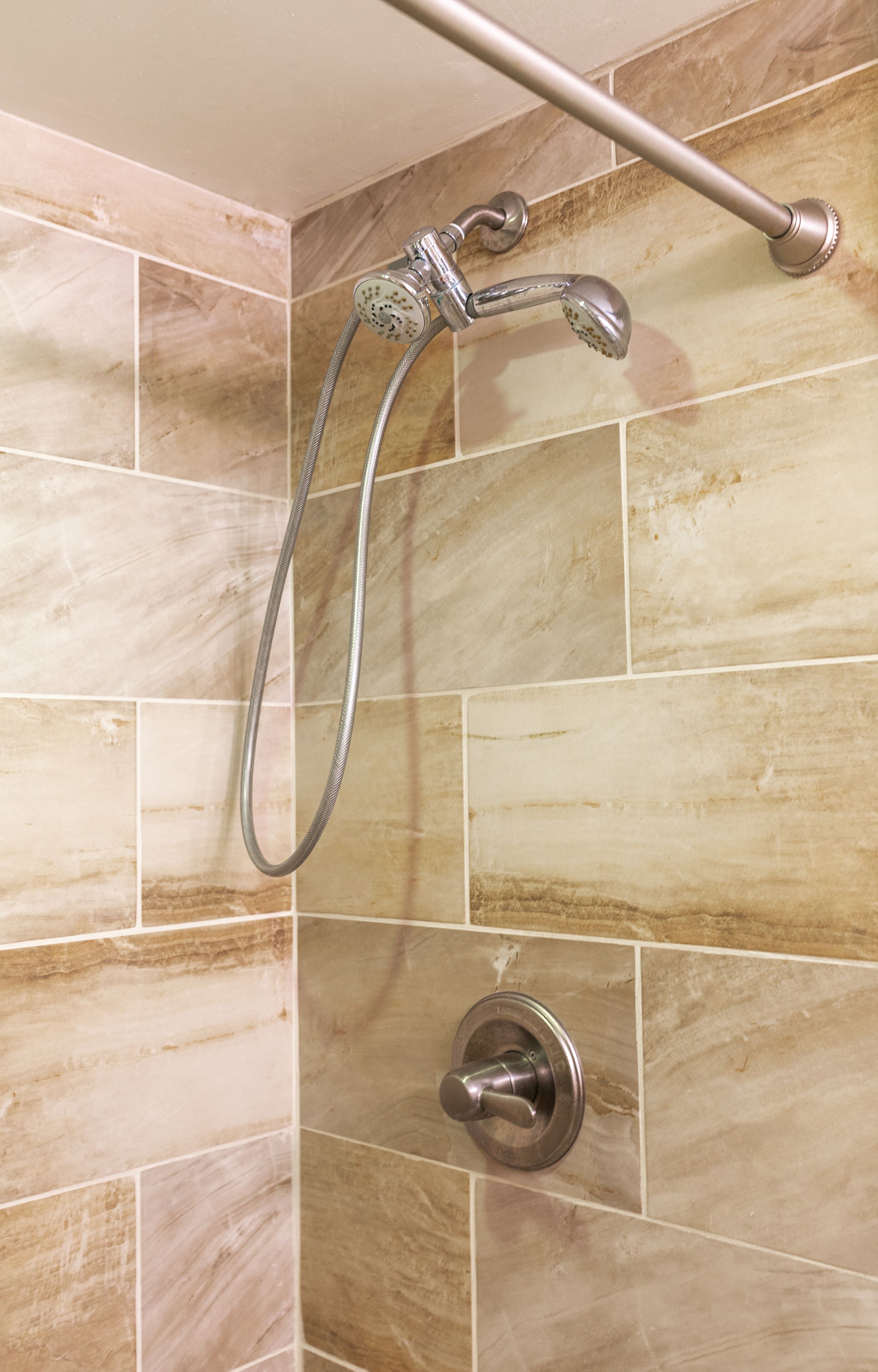 Eine Dusche mit Handbrause und Armaturen an der Wand.