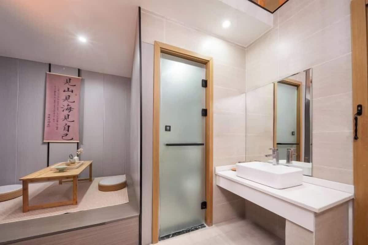 A modern bathroom with a wooden door, a white sink, and a mirror.