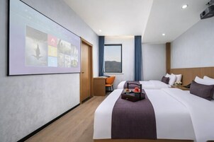 Habitación de hotel con una cama grande, un escritorio, una silla, una pantalla de proyector y una ventana con cortinas.