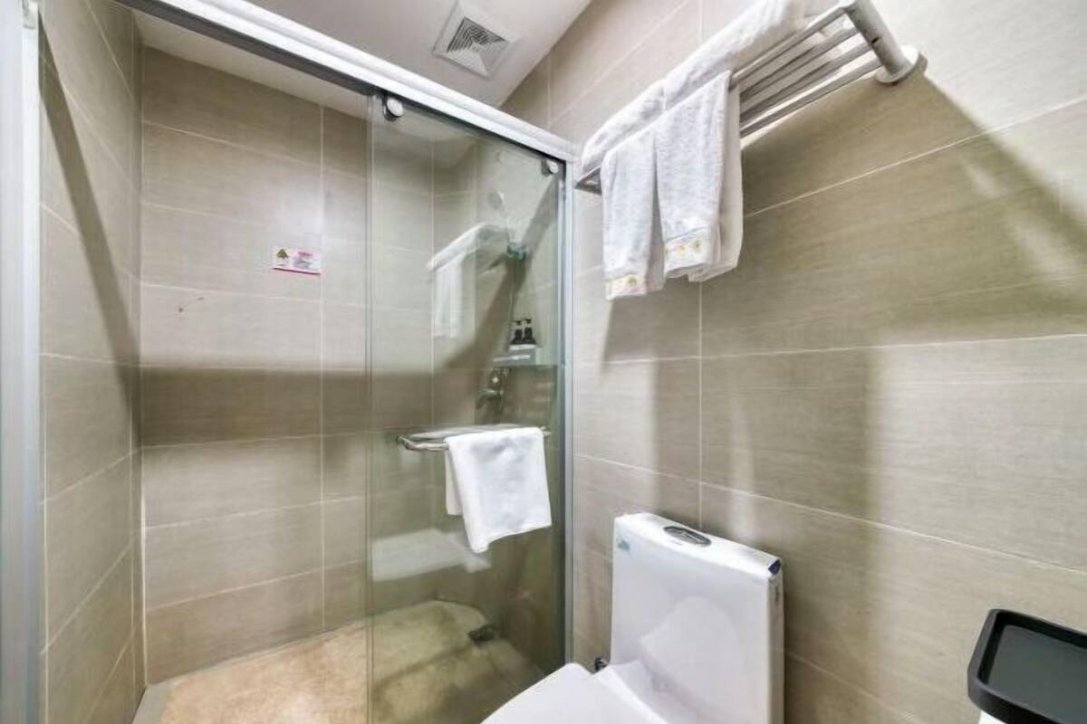 A modern bathroom with a glass-enclosed shower, a white toilet, and a towel rack.
