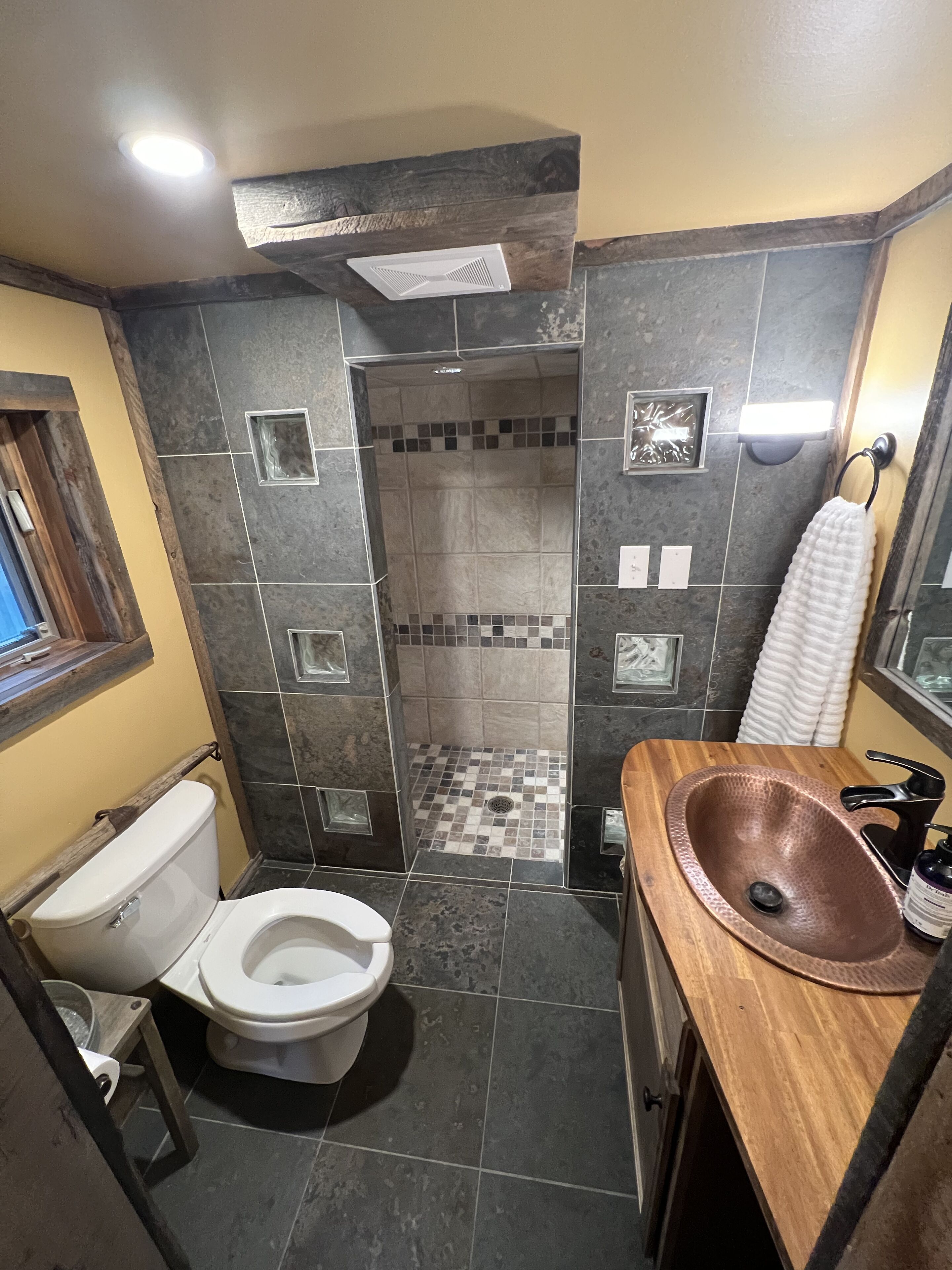 Une salle de bain équipée d’une douche, de toilettes, d’un lavabo et d’un miroir.