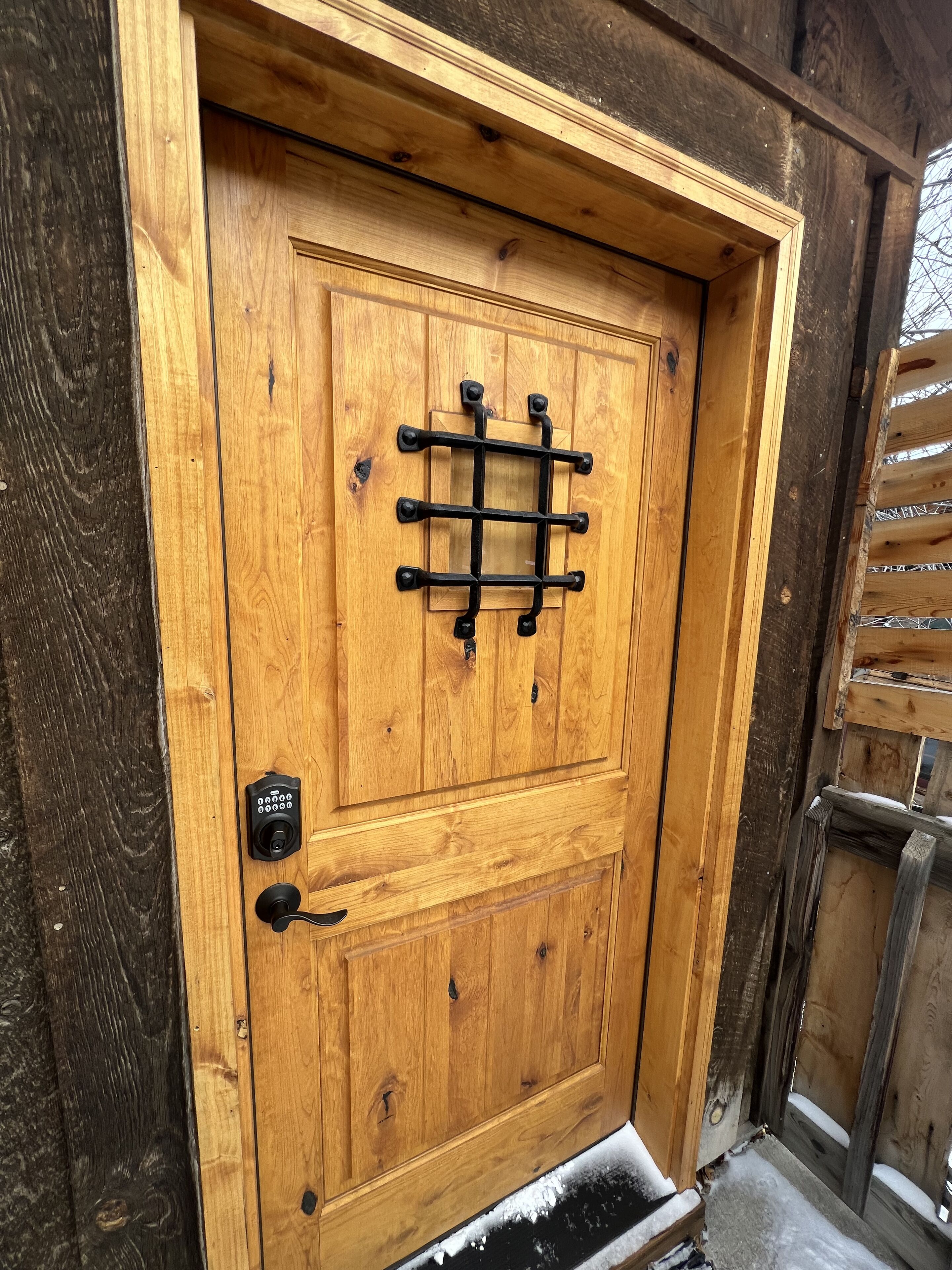 Une porte en bois dotée d’un verrou métallique à grille et d’un trou de serrure.