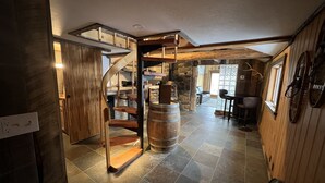 A rustic interior with a spiral staircase, stone walls, and a stone fireplace.