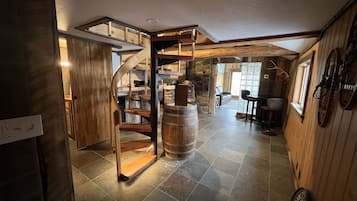 Un intérieur rustique avec un escalier en colimaçon, des murs en pierre et une cheminée en pierre.