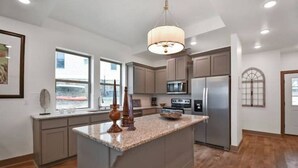 Una cocina moderna con una isla central, electrodomésticos de acero inoxidable y un amplio ventanal que proporciona luz natural.