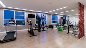 A spacious gym with a treadmill, weight machines, and a weight rack. - Residencial ID Ibirapuera (São Paulo)