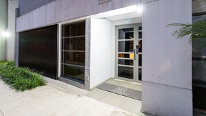 A modern building with a concrete facade, large glass doors, and a metal entrance gate. - Residencial ID Ibirapuera (São Paulo)