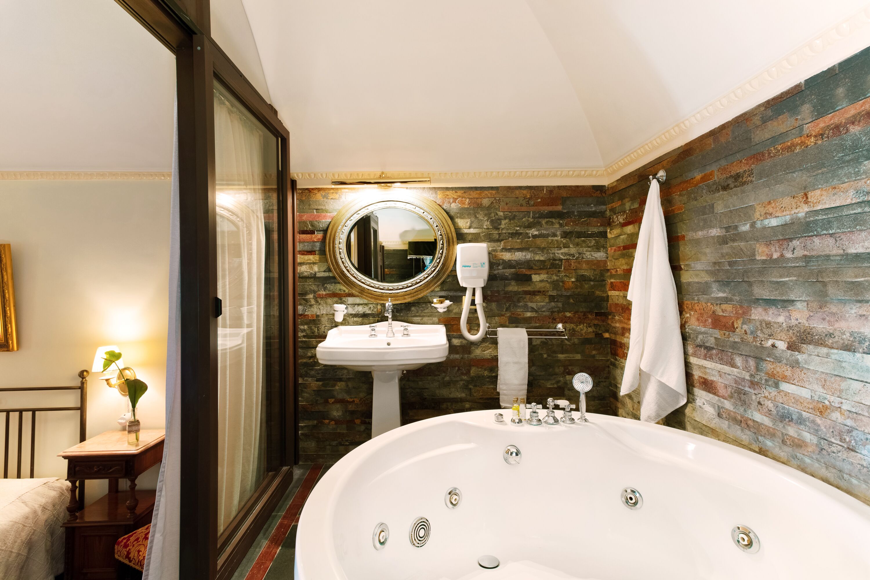 A bathroom with a large bathtub, a sink, and a mirror.