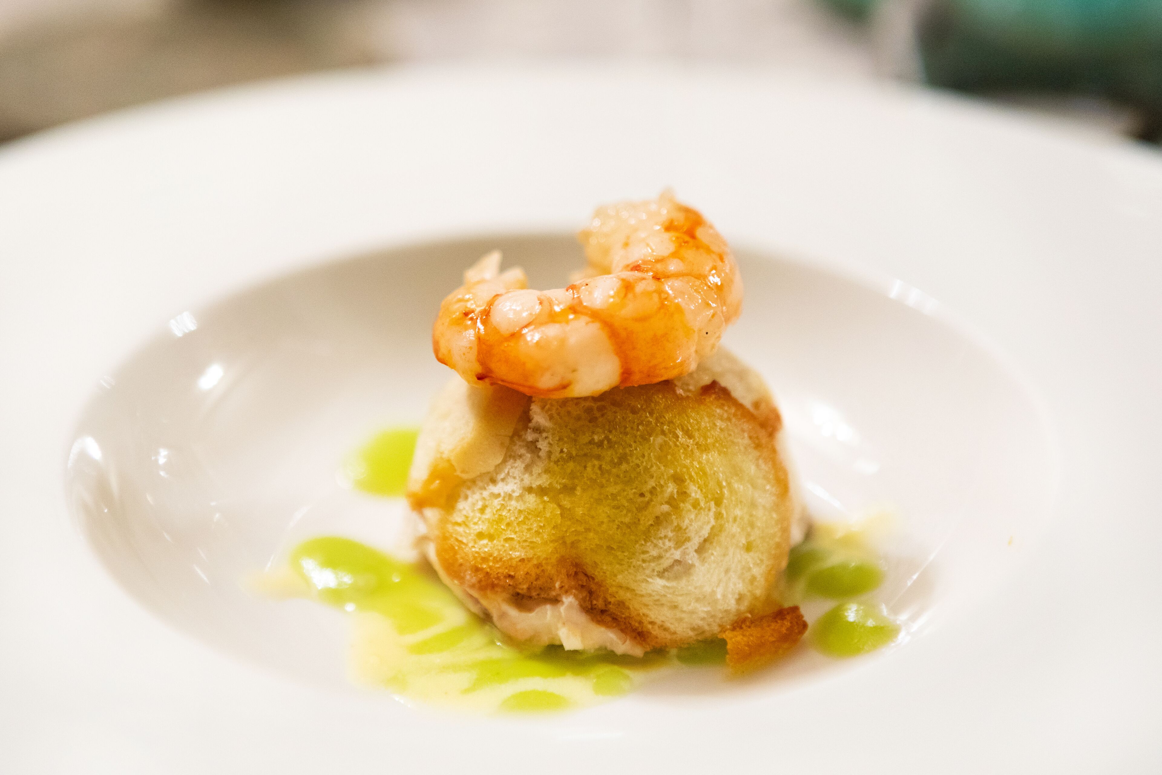 A shrimp on a piece of bread with a green sauce.